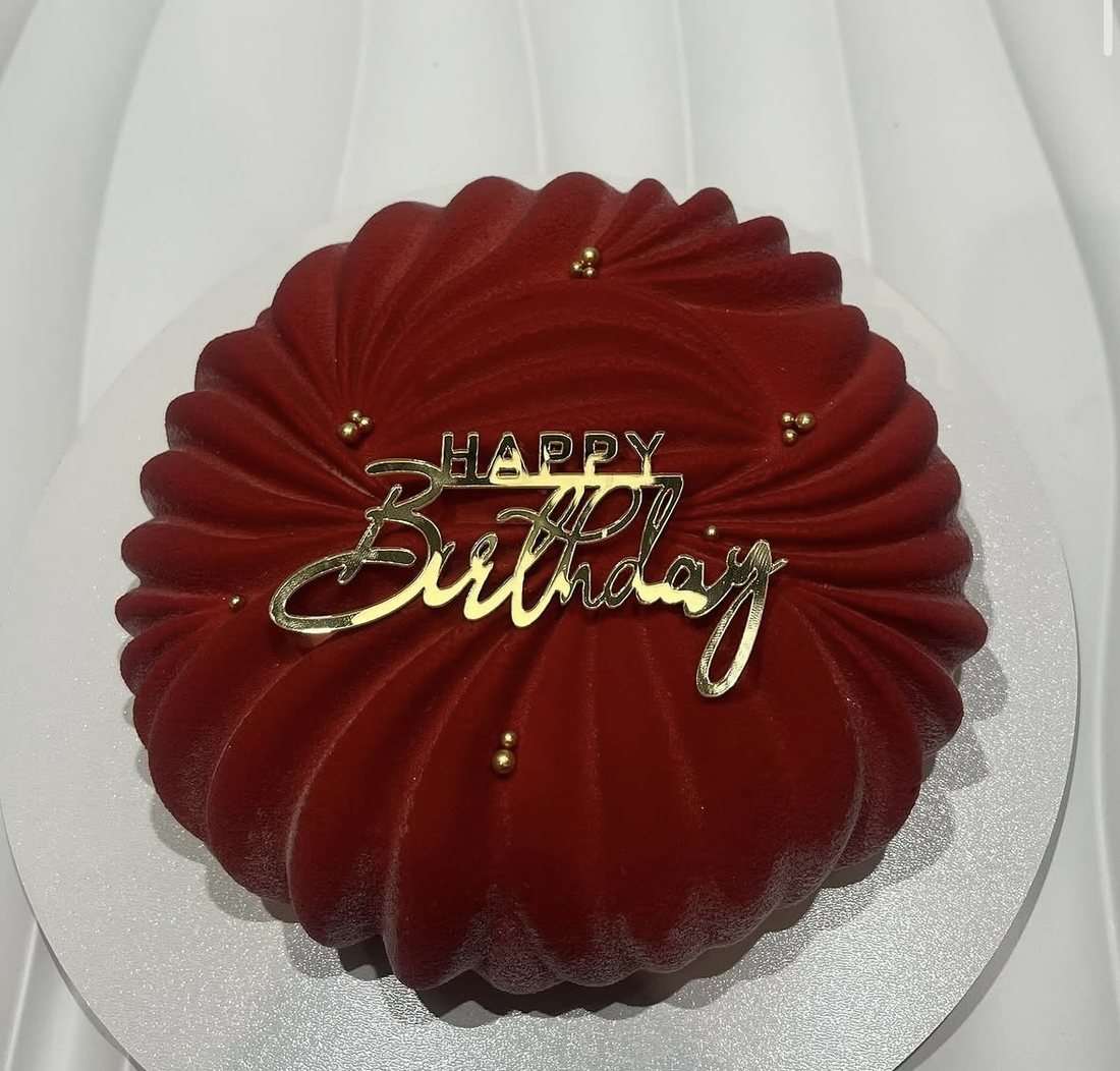 Maroon pleated mousse cake with a gold Happy Birthday topper