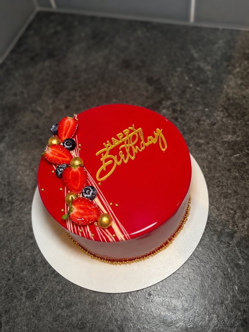 Red mirror glaze mousse cake with strawberries, blueberries and gold Happy Birthday script