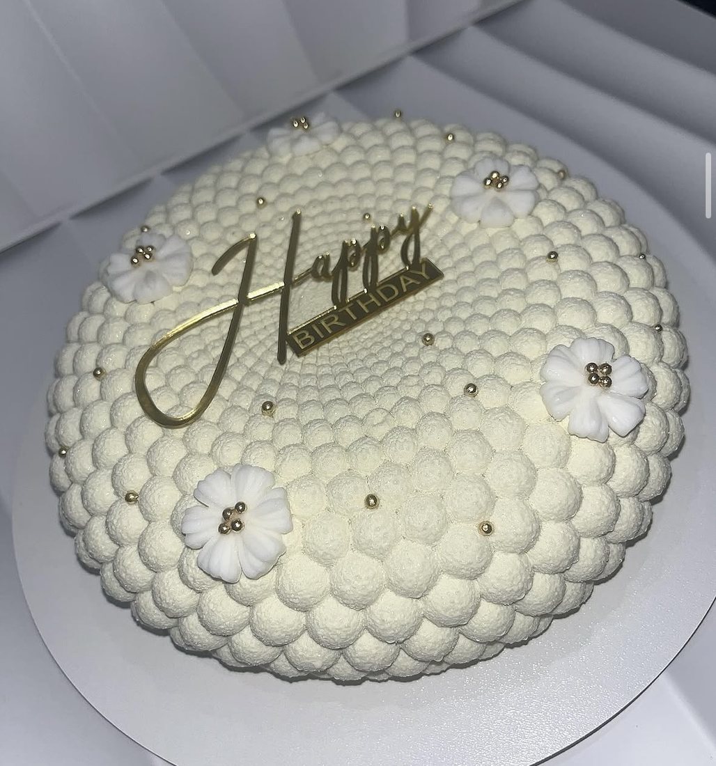 White bubble textured mousse cake with gold flowers and a Happy Birthday topper