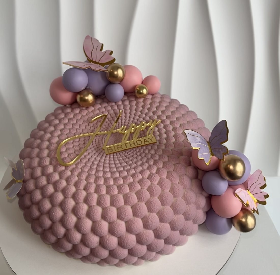 Pink and lilac bubble textured cake with butterflies and gold spheres