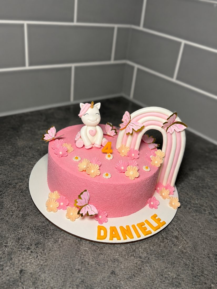 Pink unicorn and rainbow themed birthday cake with butterflies